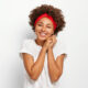 attractive-young-woman-with-afro-hairstyle-keeps-hands-pressed-together-wears-red-headband-casual-clothes